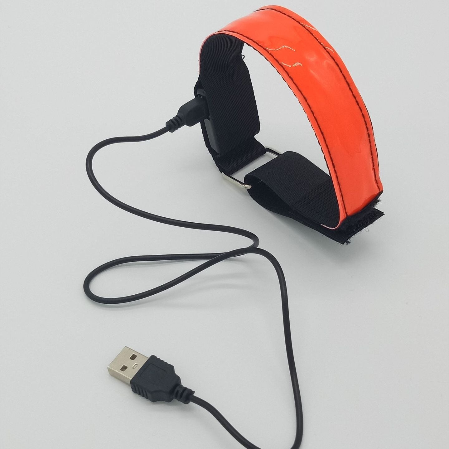 Orange reflective safety belt with USB cable on a gray background